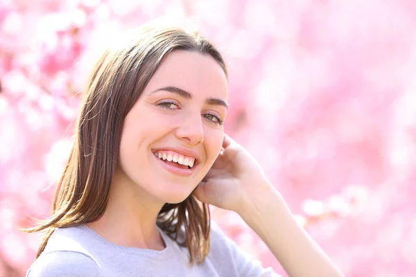 Счастливая Женщина Идеальной Улыбкой Смотрит Камеру Фоне Розовых Цветов — стоковое фото