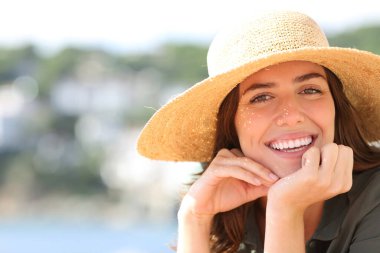 Sahilde gülümseyen mutlu bir kadın sana bakıyor.