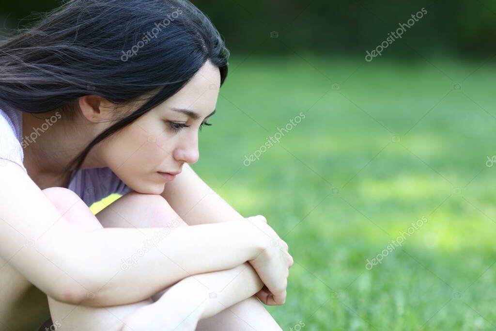 Sad asian woman complaining alone sitting in a park