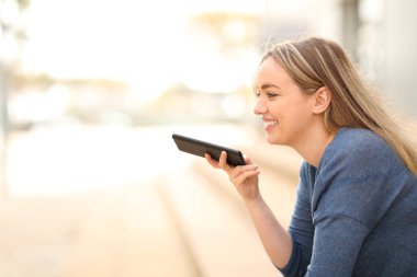 Sokaklarda oturup cep telefonuna mesaj yazdıran mutlu bir genç.