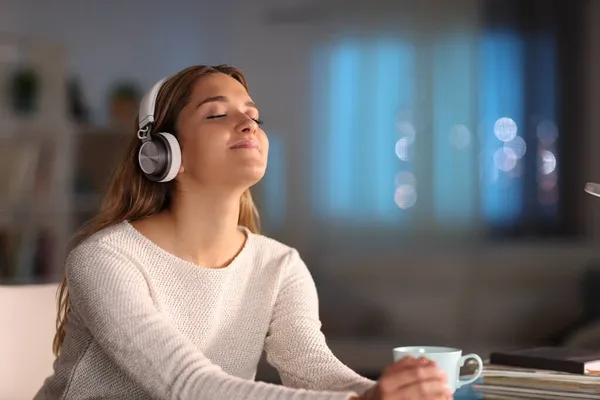 Happy Female Relaxing Listening Music Wearing Wireless Headphones Night Home — Stock fotografie