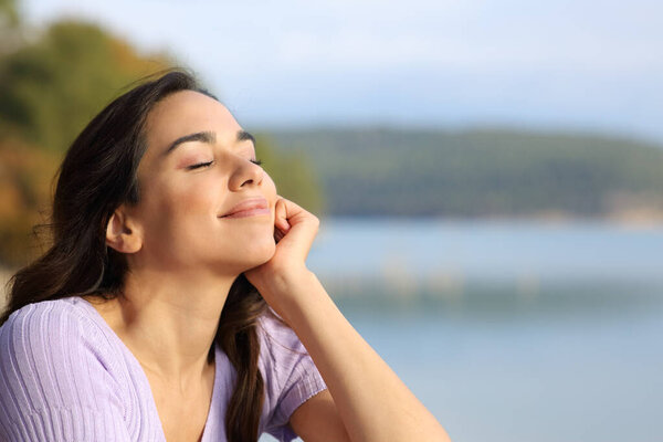 Happy woman relaxing with closed eyes sitting in the mountain