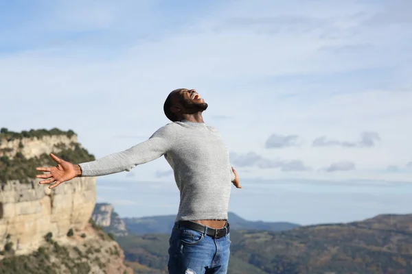 兴奋的黑皮肤男人张开双臂庆祝山里的假期 — 图库照片