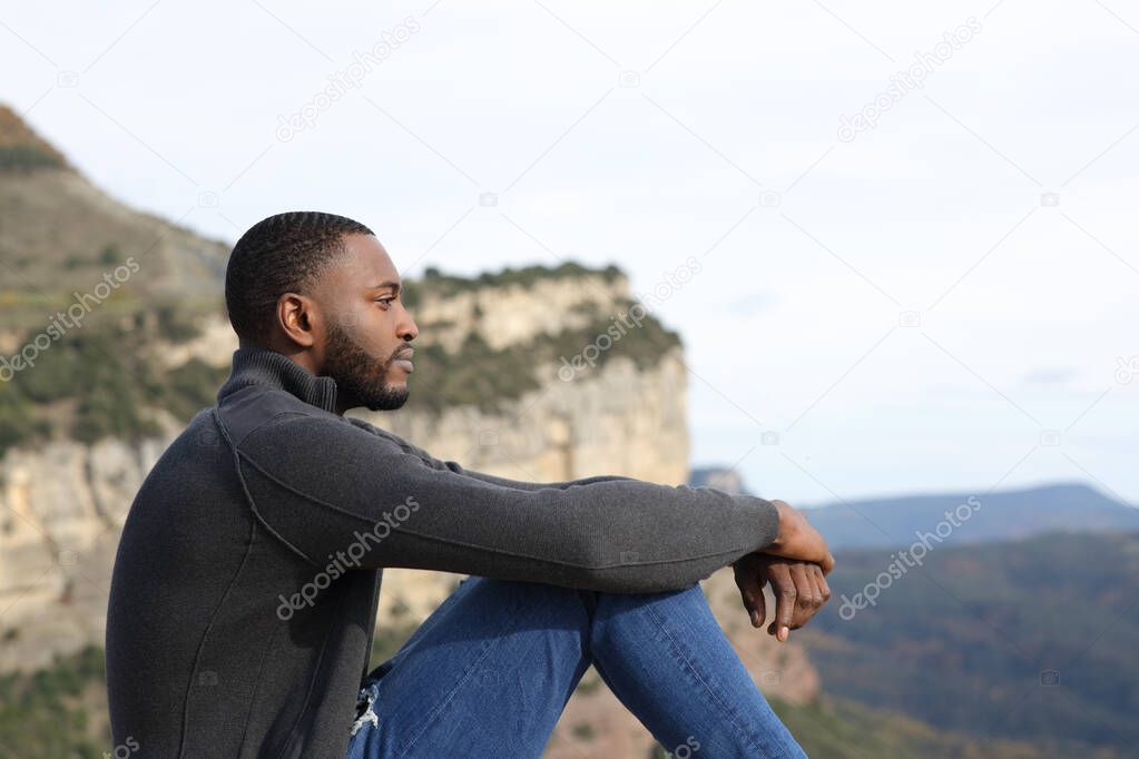 Profile of a serious man with black skin contemplating sitting in the mountain