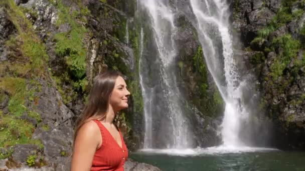 美しい滝で成功を祝う赤い腕を上げる女性 — ストック動画