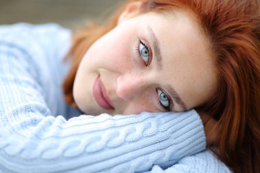 Portrait of a beauty woman with blue eyes and redhead looking at camera outdoor