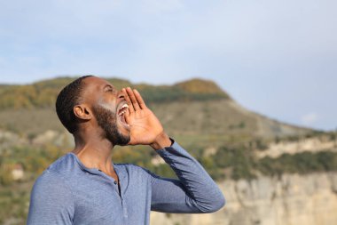 Doğada çığlık atan siyah tenli bir adamın yan görünüm portresi
