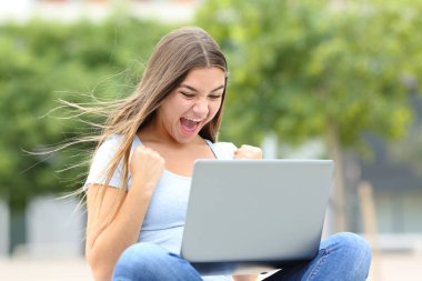 Heyecanlı gençler laptoptan iyi haberleri kontrol ediyor.