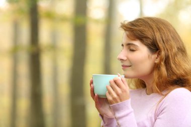 Sonbaharda ormanda kahve içen bir kadının profili.