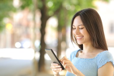 Mutlu Asyalı kadın sokakta yürürken gülümseyen akıllı telefon kullanıyor.