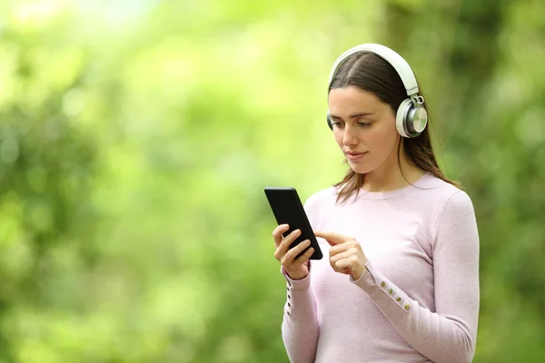 Kulaklık Takan Yeşil Arka Planda Müzik Dinleyen Bir Kadın — Stok fotoğraf