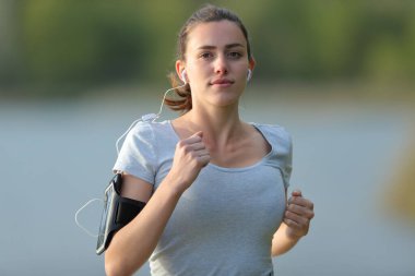 Doğada müzik dinleyen bir koşucunun ön görünüm portresi