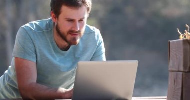 Terasta dizüstü bilgisayardaki haberi kutlayan heyecanlı adam.