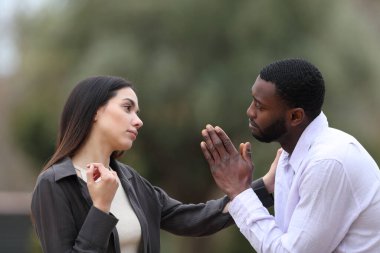 Pişman bir adam parkta bir kadına af diliyor.