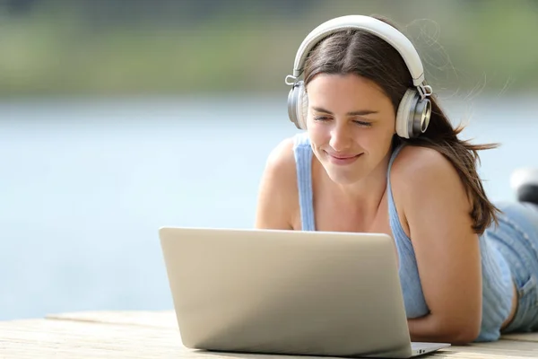 Rıhtımda Dizüstü Bilgisayar Kullanan Kulaklıklı Tatmin Olmuş Bir Kadın — Stok fotoğraf