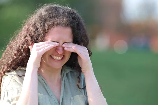 一个紧张的女人在公园里走来走去 挠痒痒的眼睛 — 图库照片