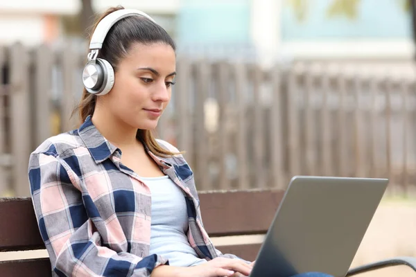 Konsantre Öğrenci Öğrenimi Parktaki Bankta Dizüstü Bilgisayar Kulaklıkla — Stok fotoğraf