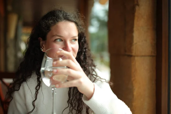 快乐的女人拿着杯子喝水 从窗口往里看 — 图库照片
