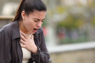 Stressed woman having problems to breath sititng in a park