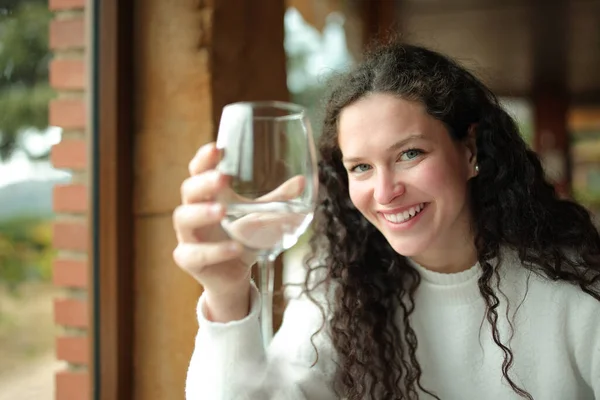 一个快乐的女人坐在餐厅的内部 手里拿着一杯水 — 图库照片