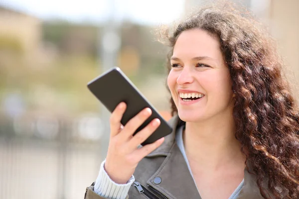快乐的女人在街上用手机上的语音识别大笑 — 图库照片