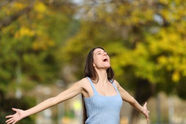 Heyecanlı genç çığlıklar atıyor kollarını açıp parkta dikiliyor.