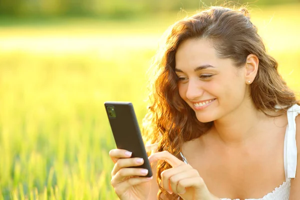 日落时分 快乐的女人在麦田里用智能手机 — 图库照片