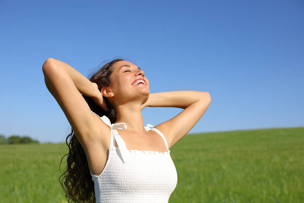 Happy woman laughing and breathing fresh air in a field  in summer