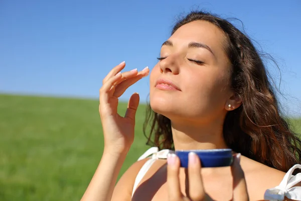 Mulher Aplicando Creme Hidratante Seu Rosto Campo Dia Ensolarado — Fotografia de Stock