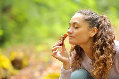 Ormandaki ölü yaprakların kokusunu alan mutlu kadın.
