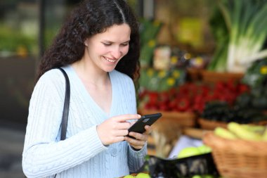Müşteri manavda akıllı telefon kullanıyor.