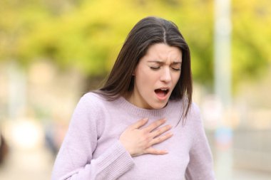 Stressed teen having breath problems standing in a park