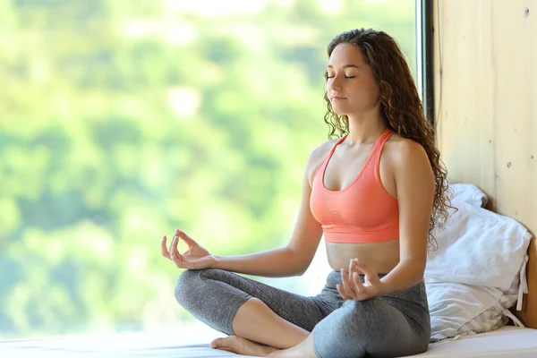 Woman doing yoga exercise in a room near a window