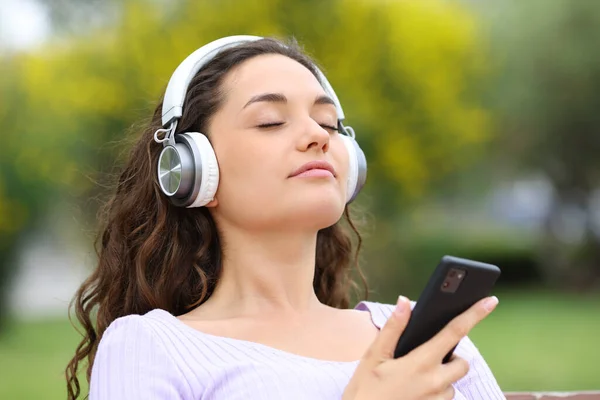 Relaxed Woman Wearing Headphones Holding Smart Phone Meditating Listening Guide — Foto Stock