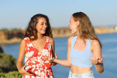 Yaz tatilinde iki mutlu arkadaş sahilde konuşuyor.