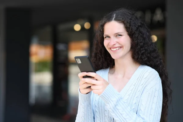 Ευτυχισμένη Γυναίκα Κρατά Έξυπνο Τηλέφωνο Και Κοιτάζει Κάμερα Στέκεται Στο — Φωτογραφία Αρχείου