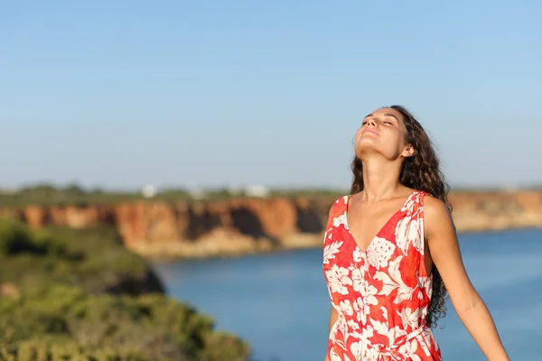 海岸の崖の上で新鮮な空気を呼吸する赤い女性 — ストック写真