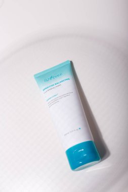 İzmail, Ukrayna, Temmuz 2021. Beyaz masa üzerinde mavi başlıklı beyaz tüp, ilginç gölgeler oynuyor. Yüz bakımı kozmetikleri, krem