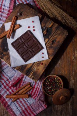 Acı biberli koyu acı çikolata, tarçın, beyaz kağıtta kırmızı bezelye aromalı kırmızı biber aromalı tahta arka plan. Alışılmadık tatlar