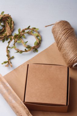 El yapımı Noel hediyeleri paketleme işlemi. Kağıt, kutu ve jüt halat makarası beyaz masada. Kış tatili çevre dostu çalışma.