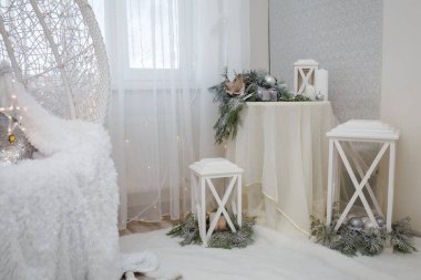 Güzel Noel süslemeleri, köknar dallarında beyaz takılar, fener ve beyaz masada mumlar. Kış tatili, yeni yılın büyüsü