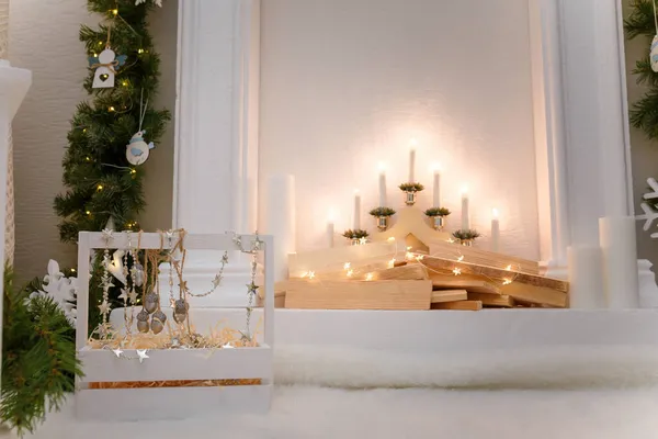 木製の装飾暖炉 キャンドルや光沢のあるガーランドライトボケ モミの枝 クリスマスの装飾 お祝いの詳細 — ストック写真