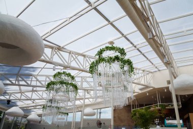 Dekoratif yeşil sarmaşık bitkisi olan güzel beyaz avizeler açık hava restoranının iç tarafında.