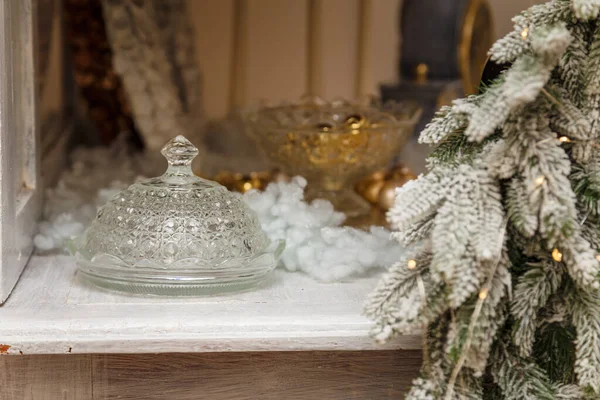 人工雪の中の食器棚に立つキャンディーのための装飾的なガラスの花瓶 金色のガーランドライトボケとモミの枝 メリークリスマス — ストック写真