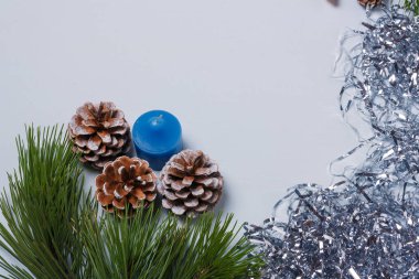 Mutlu Noeller, mutlu yıllar kartpostalı, şablon. Çam ağacı dalları, boyalı koniler, mavi mum, gümüş süsleme kenarı. Boşluğu kopyala