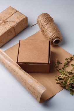 El yapımı Noel hediyeleri paketleme işlemi. Kağıt, kutu ve jüt halat makarası beyaz masada. Kış tatili çevre dostu çalışma.