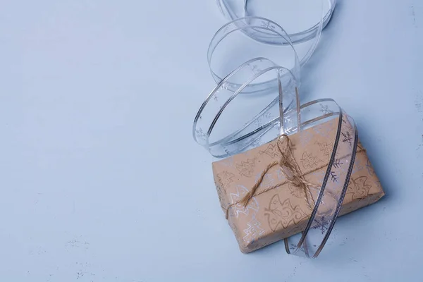 クリスマスプレゼントボックス包装 クラフト紙 ジュートロープ弓 ライトブルーの背景に銀リボンテープ 新年カード コピースペース — ストック写真