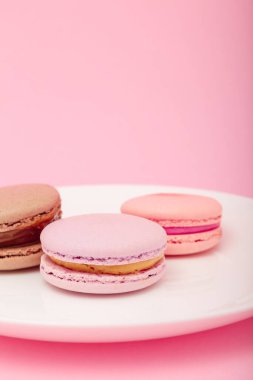 Pembe kağıtta beyaz tabakta üç badem kurabiyesi. Tatlı fırın, kopyalama alanı. Aşırı kilolu, diyet, diyabet, sağlıklı beslenme alışkanlıkları.