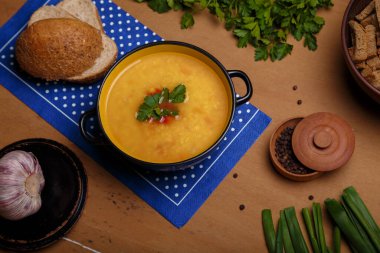 Maydanozlu mercimek ya da bezelye çorbası, soğan, sarımsaklı ahır ekmeği ve ahşap masa üzerinde çavdar krakeri. Organik yiyecekler, sağlıklı beslenme. Üst görünüm.