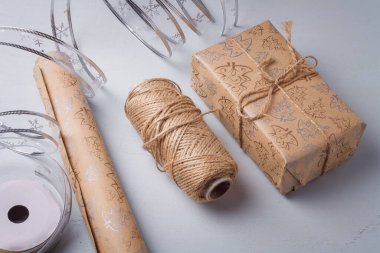 Mutlu Noeller hediye kutusunun paketlenmesi devam ediyor. Kraft kağıdı, arka planda gümüş şerit bant makarası. Çevre dostu ambalaj